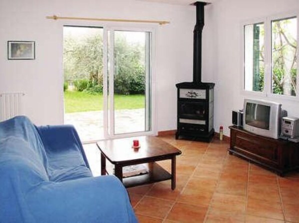 A living room with a sofa, a television, a fireplace, and a view of the outdoors. - Sylviane House (Pietrabruna)