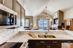 Una cucina moderna con una grande isola, elettrodomestici integrati e vista sull'area living.