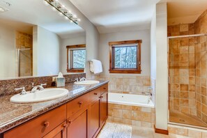 Une salle de bain avec deux lavabos, un grand miroir, une baignoire et un espace douche.