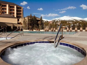 Un bain à remous avec une barrière en métal, une piscine et une montagne en arrière-plan.