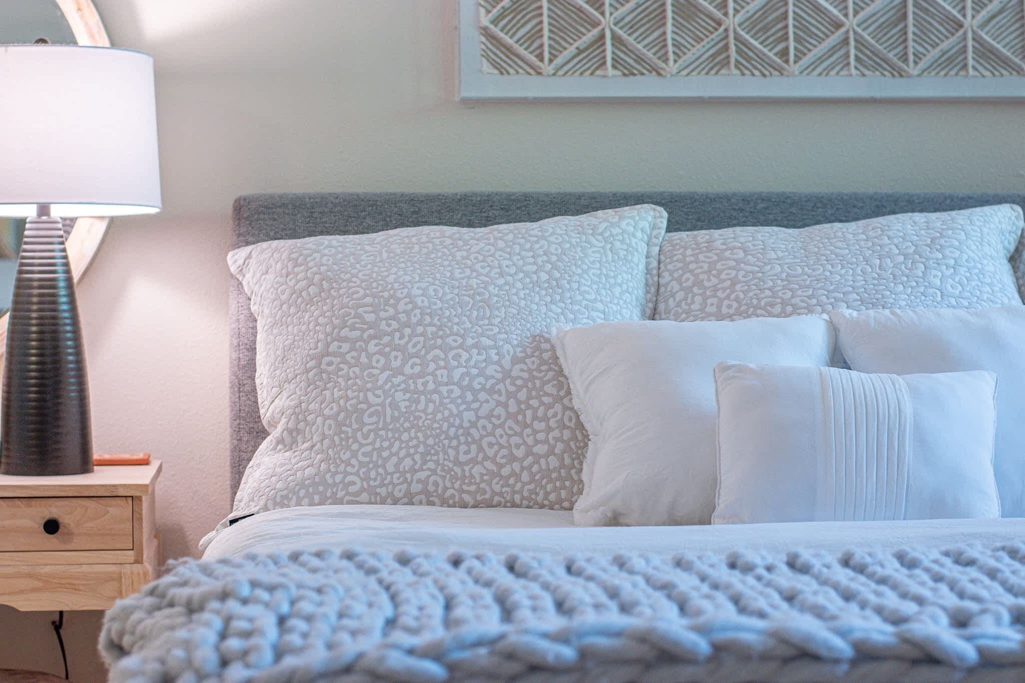 A bed with patterned pillows, a bedside lamp, and a textured blanket.