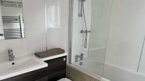 A modern bathroom with a white sink, dark wooden cabinets, a white toilet, and a glass-enclosed shower area. - The Mews, With Free Private Parking, Windermere (Windermere)