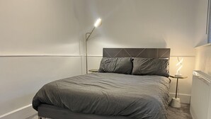 A modern bedroom with a bed, a bedside table, a floor lamp, and a radiator. - The Mews, With Free Private Parking, Windermere (Windermere)