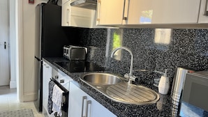 A modern kitchen with a black granite countertop, stainless steel sink, and a toaster. - The Mews, With Free Private Parking, Windermere (Windermere)
