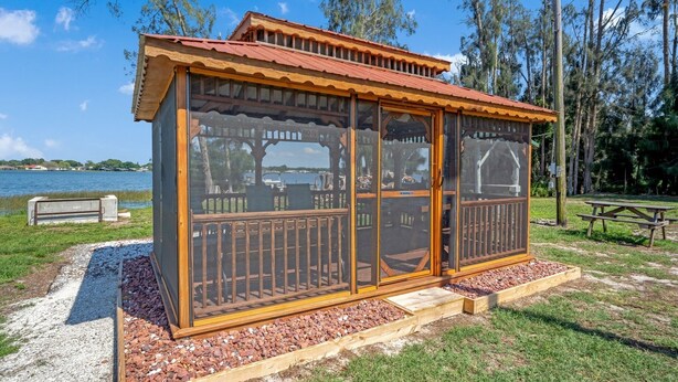 A wooden gazebo with a red roof, glass doors, and a wooden railing. - Lake Placid Home Boat Parking and Clubhouse Access by RedAwning (Lake Placid)