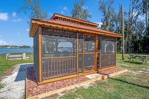 A wooden gazebo with a red roof, glass doors, and a wooden railing. - Lake Placid Home Boat Parking and Clubhouse Access by RedAwning (Lake Placid)