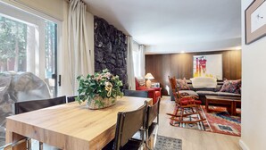 Ein modernes Wohnzimmer mit einer Steinwand, einem Holztisch und einer Couch mit gemusterten Kissen.