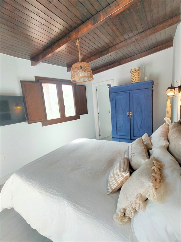 A bedroom with a large bed, wooden ceiling beams, a blue wardrobe, and a hanging light fixture. - Villa Aura, a beautiful home located in a natural setting (El Ingenio de Santa Lucia)