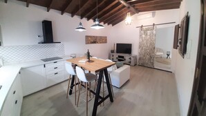 Una cocina moderna con armarios blancos, una mesa de comedor de madera y un televisor.