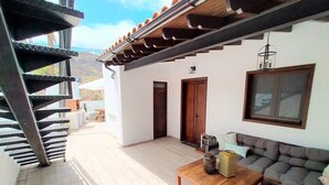 Un patio moderno con una mesa de madera, un sofá y una escalera.