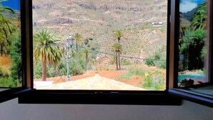 Una habitación con un ventanal grande que ofrece vistas a un paisaje montañoso con palmeras.
