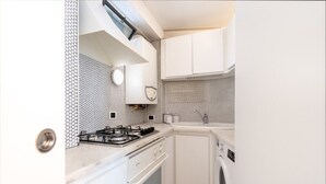 A compact kitchen with a gas stove, oven, microwave, and a washing machine.