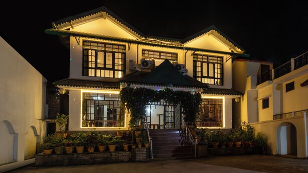 A two-story building with a traditional architectural style, featuring a balcony and a staircase leading to the entrance. - Treebo Spring Birds - 3Kms from Bhimtal Lake (Nainital)