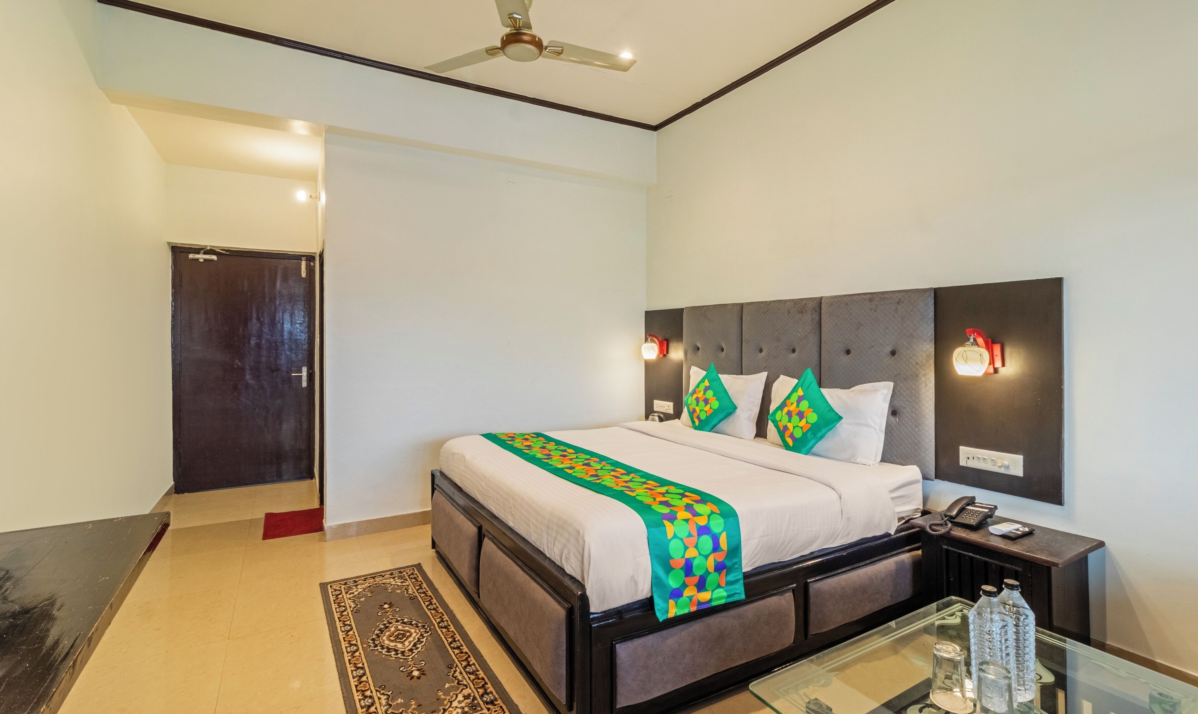 A neatly arranged hotel room with a bed, bedside table, and a nightstand.