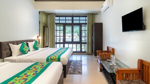A hotel room with two beds, a desk, a TV, and a window with curtains. - Treebo Spring Birds - 3Kms from Bhimtal Lake (Nainital)