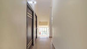A long, narrow hallway with a door on the left and a window at the end. - Treebo Spring Birds - 3Kms from Bhimtal Lake (Nainital)