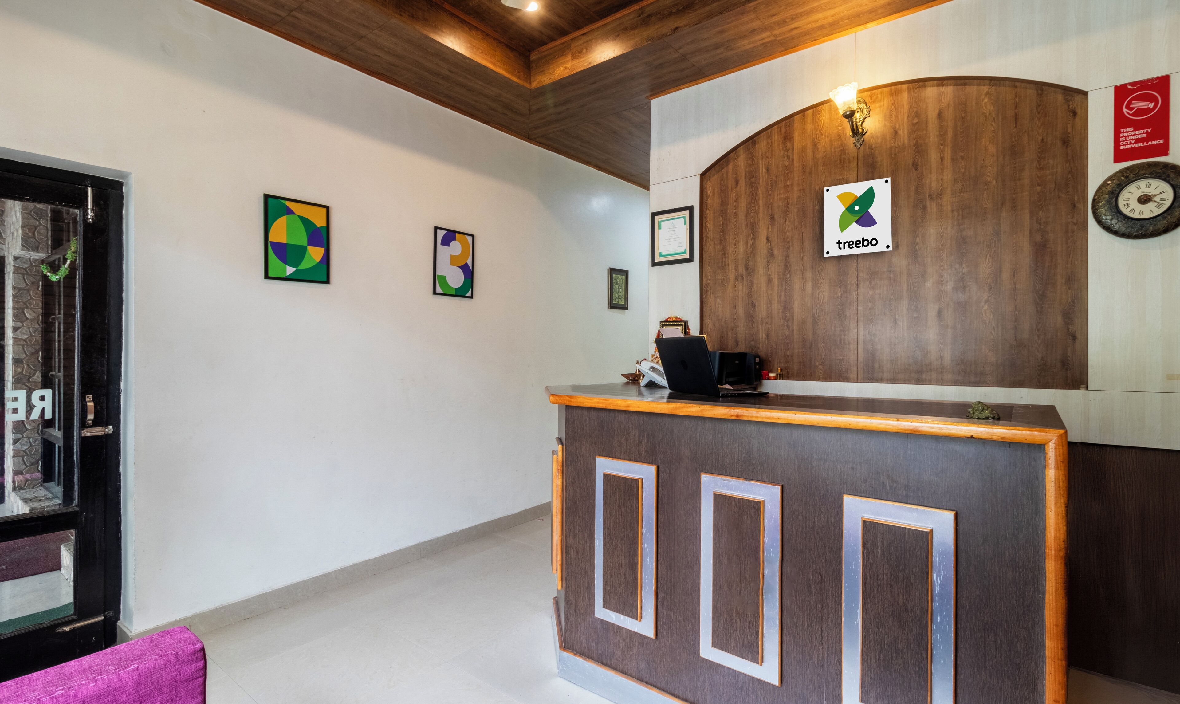 A reception area with a wooden reception desk, framed artwork on the walls, and a clock.