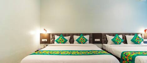 Habitación de hotel con dos camas, cada una con una colcha blanca y un plaid verde estampado.