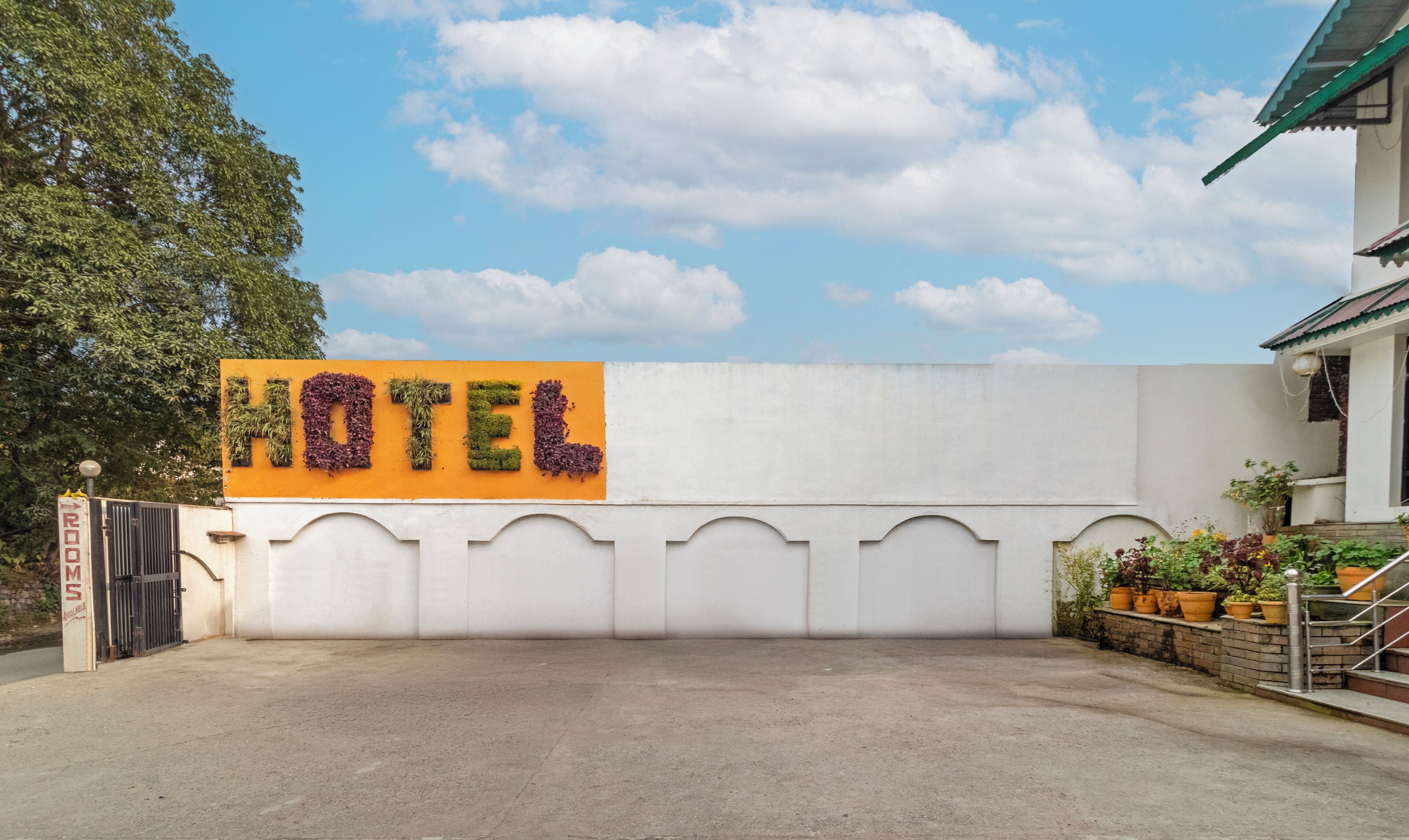 A hotel entrance with a sign spelling "HOTEL" in large letters, a gated entrance, and a staircase leading to the building.
