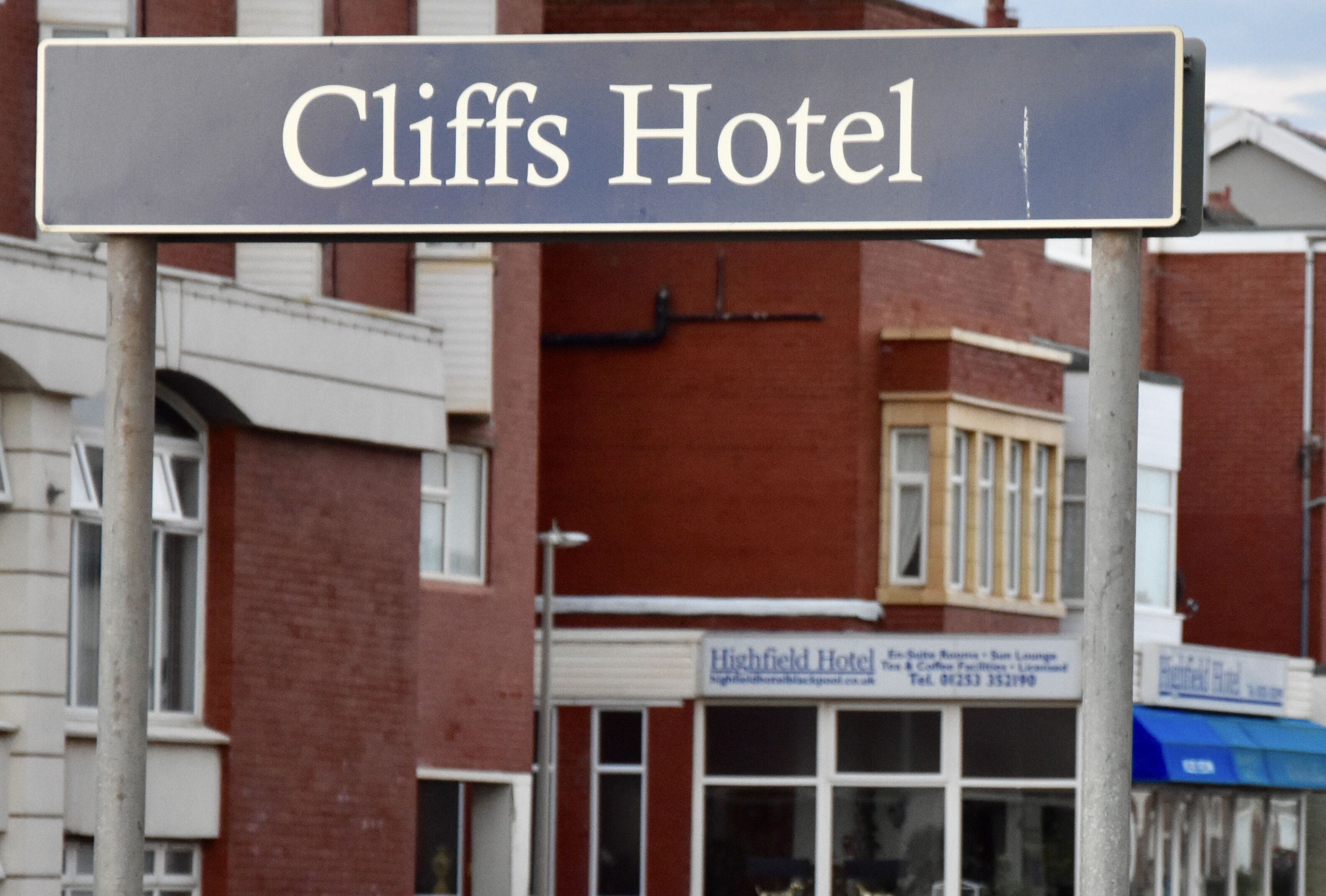 A hotel sign for 'Cliffs Hotel' with a clear view of the building's facade, including a window and a door.