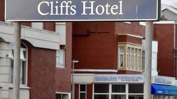 A hotel sign for 'Cliffs Hotel' with a clear view of the building's facade, including a window and a door.