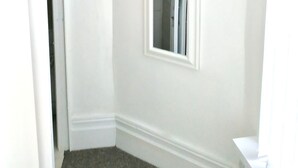 A corner room with white walls, a small window, and a door leading to another room. - Studio for 2 (ground floor) in fashionable North Shore (Blackpool)