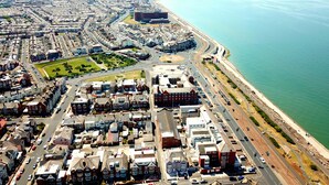 An aerial view of a coastal city with a mix of residential and commercial buildings, a prominent bridge, and a coastline. - Studio for 2 (ground floor) in fashionable North Shore (Blackpool)