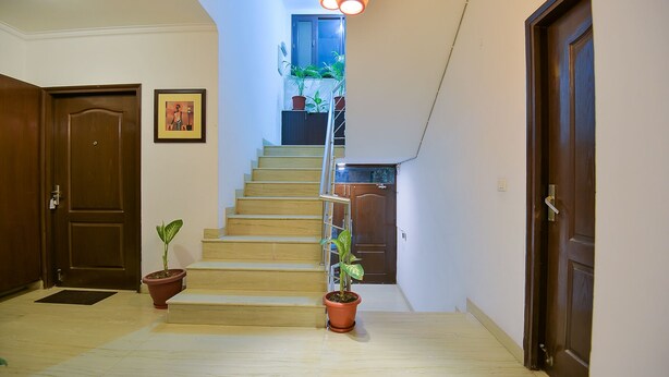A staircase leading to a balcony with potted plants and a door on the left.