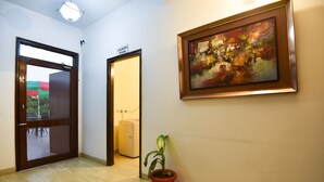 A hallway with a sign indicating a laundry room, a potted plant, and a painting on the wall.