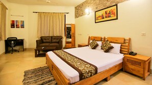 A hotel room with a wooden bed, a desk, a leather chair, and a small table.
