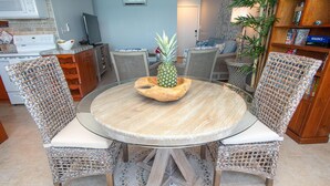 A round wooden table with a woven chair design, a pineapple centerpiece, and a tiled floor. - 1BR/1BA New Oceanside Condo (Charlotte Amalie)