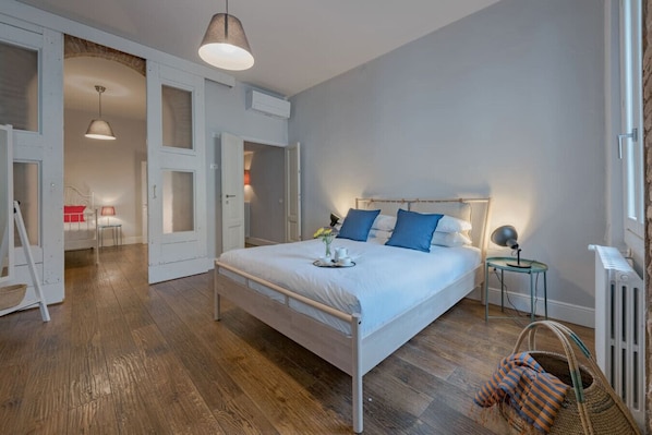 A bedroom with a large bed, a bedside table, a lamp, and a radiator.