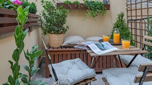A cozy outdoor seating area with a wooden table, cushioned chairs, a woven planter, and a magazine. - Guelfa Apartment  (Firenze)