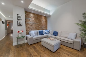 Uma sala de estar moderna com um sofá seccional, uma mesa de centro e uma parede de destaque em pedra.