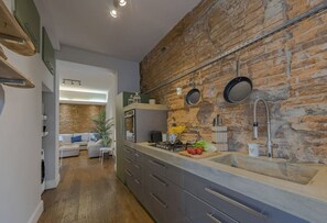 A modern kitchen with a stone wall backsplash, a built-in oven, and a large sink. - Guelfa Apartment (Firenze)