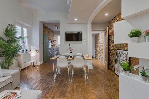 Un salon moderne comprenant un coin repas, une cuisine et un mur en pierre.
