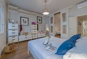 Une chambre à coucher comprenant un lit, une commode, une coiffeuse et une porte donnant sur une autre pièce.