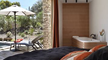 A bedroom with a large bed, a bathroom with a bathtub, and a patio area with a table and chairs.