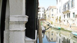 A canal with boats, a bridge, and buildings with balconies.