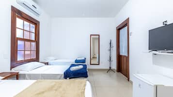 A hotel room with two beds, a TV, an air conditioner, and a coat rack.