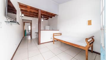 A bedroom with a wooden bed, a TV mounted on the wall, and a tiled floor.