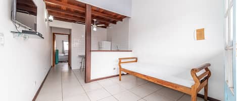 A bedroom with a wooden bed, a TV mounted on the wall, and a tiled floor.