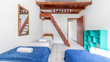 A room with two beds, a wooden staircase, a mirror, and a teal storage unit.