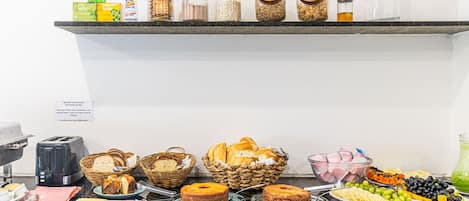 Un buffet con diversi cibi, tra cui pane, pasticcini e frutta.