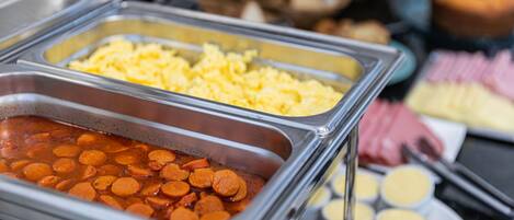 A buffet with various food items including scrambled eggs, sausage, and other dishes.