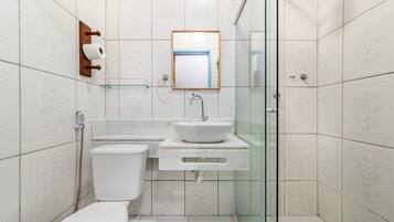 Une salle de bain moderne équipée de toilettes, d’un lavabo et d’une douche à parois en verre.