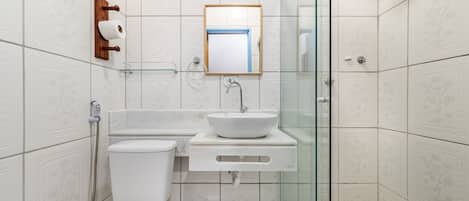 Un baño moderno con inodoro, lavabo y cabina de ducha de vidrio.