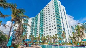 Un hotel moderno de gran altura con varios balcones, piscina y palmeras.