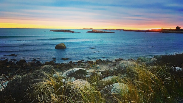 A coastal landscape with rocky shores, calm sea, and distant landforms under a clear sky. - Romantic Vineyard Retreat (Little Compton)