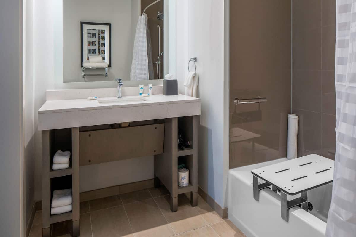 Een moderne badkamer met een wit wastafelmeubel, spiegel en douchegedeelte.